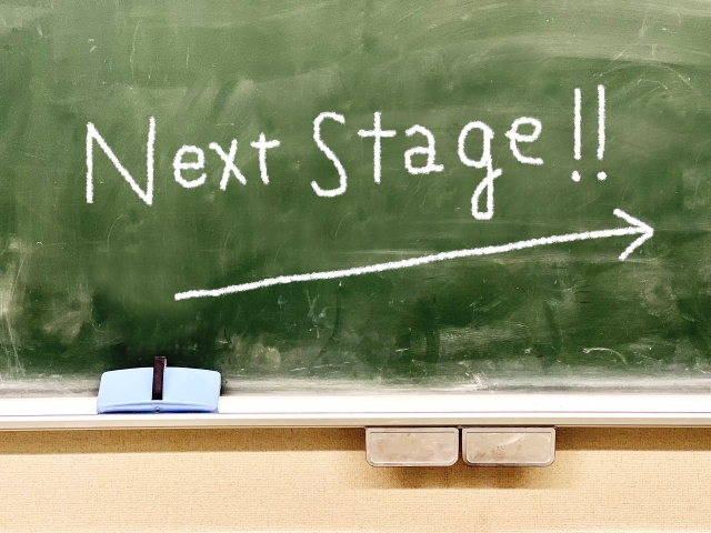 黒板に書かれた「next stage」の文字ち右肩上がりの矢印