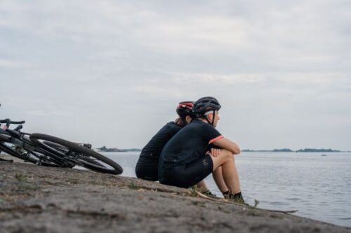 自転車から降りて海辺で海を眺める男女