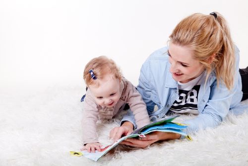 寝転んで絵本を見る母と赤ちゃん