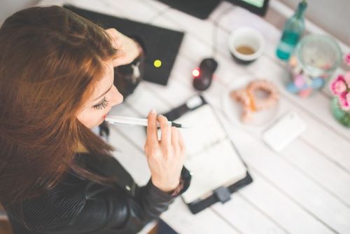 リモラボでの仕事のイメージ。ペンを持って考える女性。